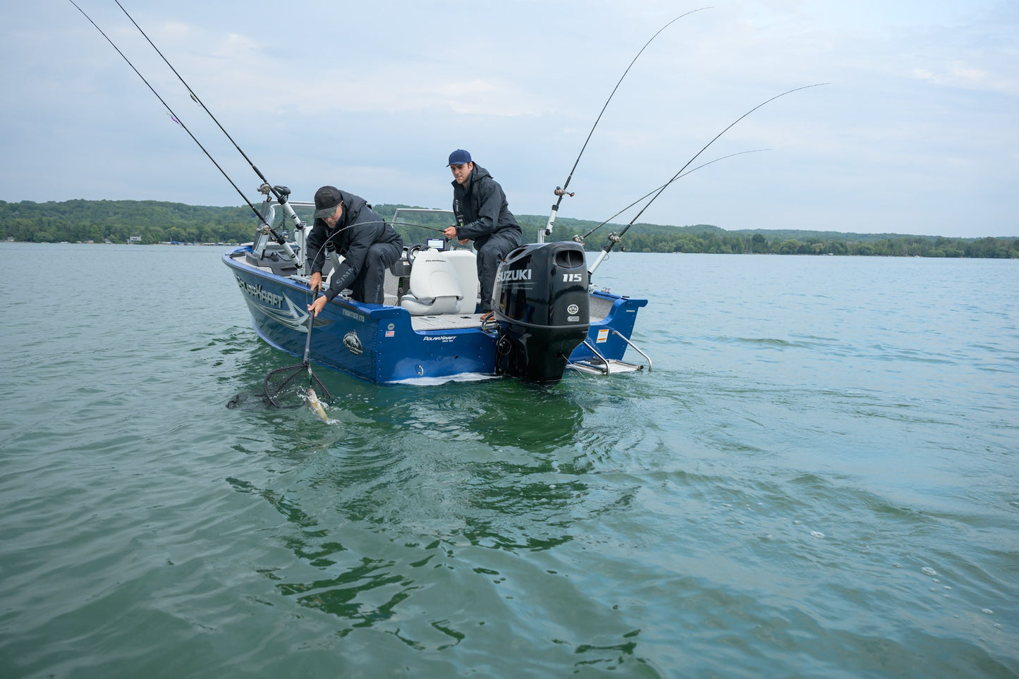 Two people fishing from a blue boat on a calm lake with a Suzuki 115