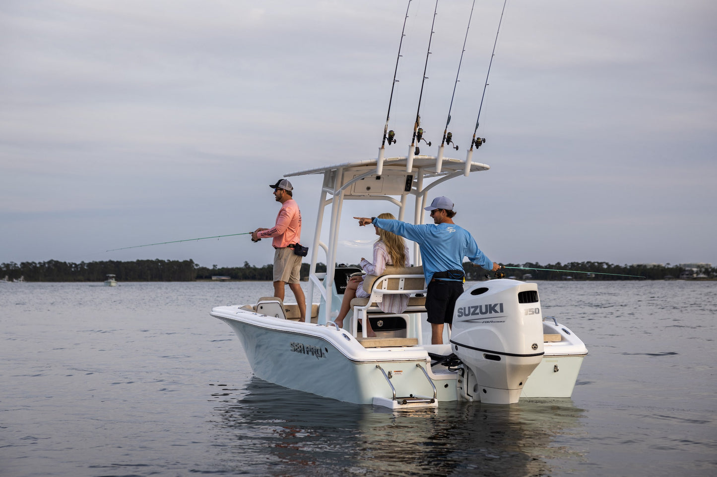 Two people on a boat with a Suzuki 150 Hp motor, fishing on a calm body of water.