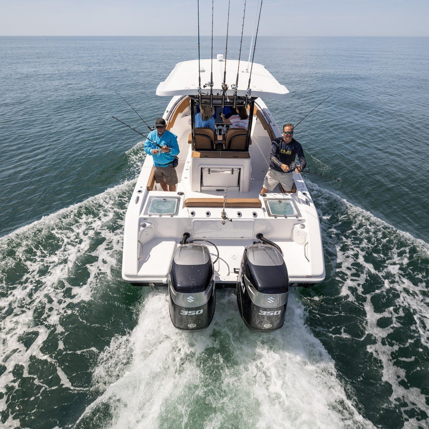 Fishing boat with two people on a clear day over water with Twin Suzuki 350