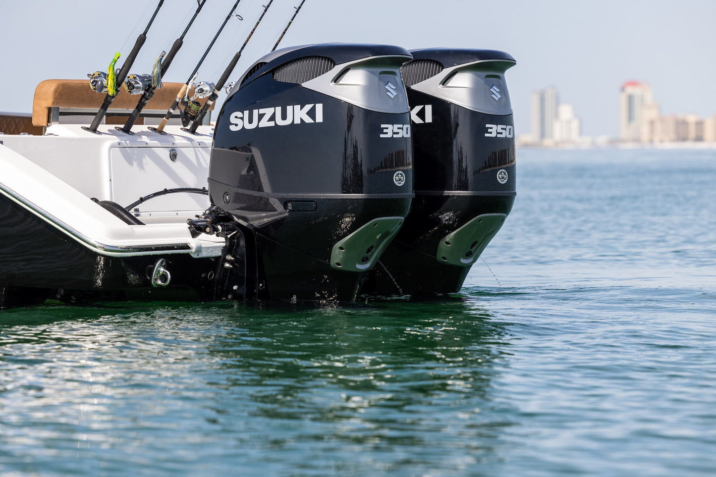 Two Suzuki 350 HP outboard motors on a boat with a city skyline in the background.