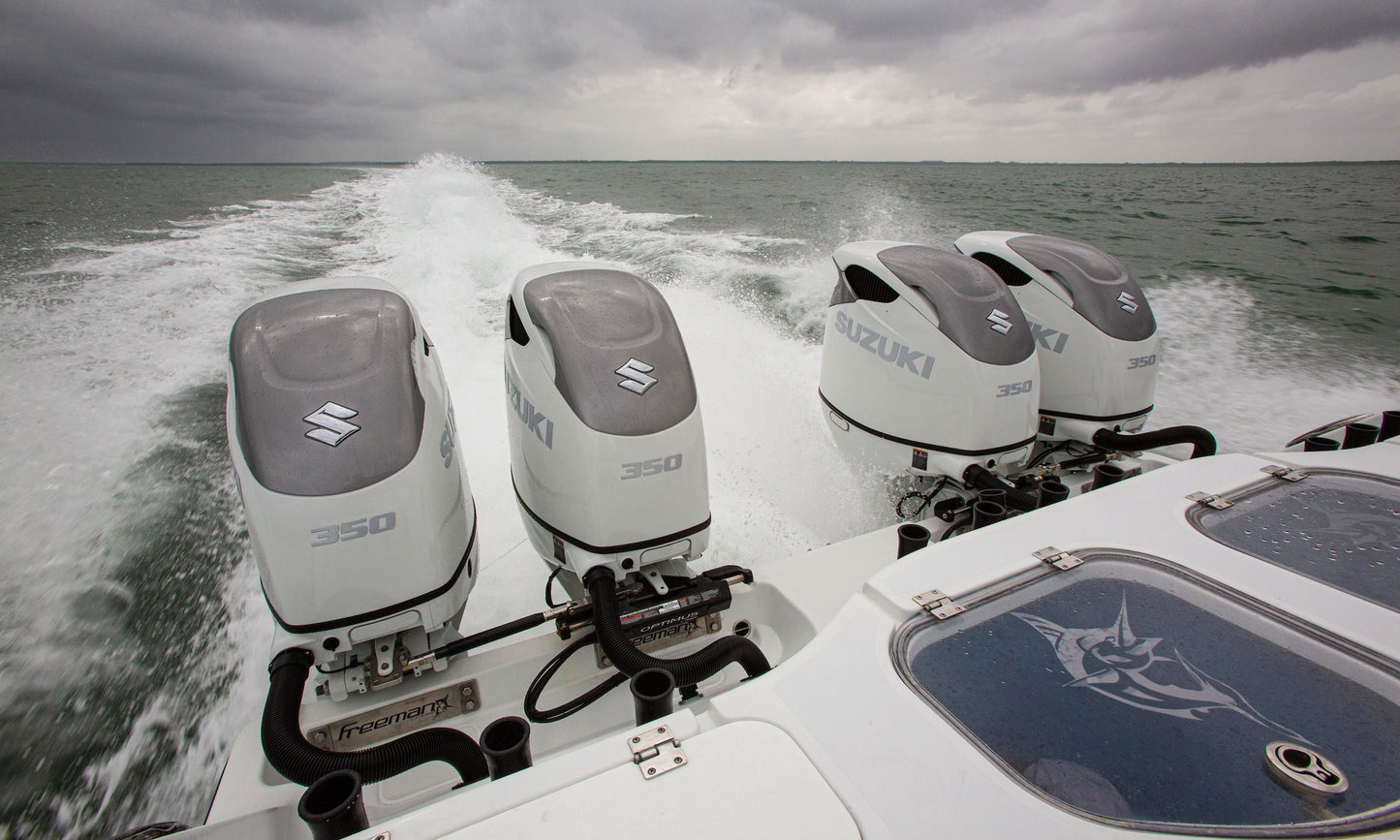 Four Suzuki 350 outboard motors on a boat with a cloudy sky and water background